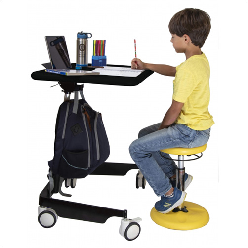 Flexible seating arrangement showing a boy sitting on a Kore Wobble Stool and working at a Kore Sit to Stand Mobile desk.