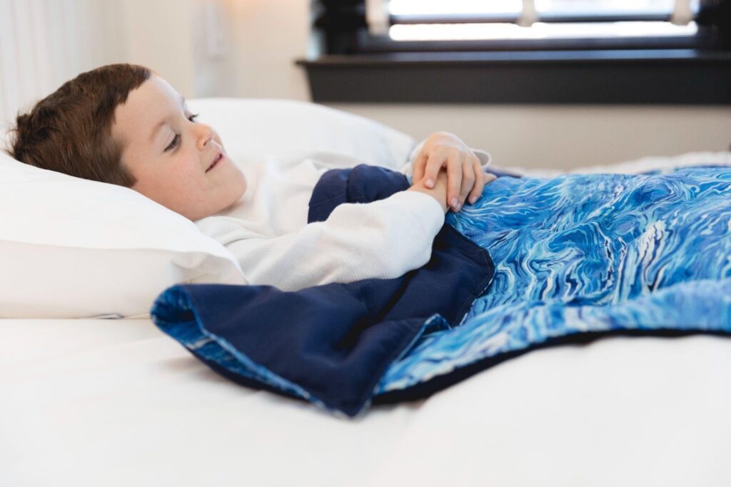 boy laying with Sommerfly Sleep Tight Weighted Blanket 